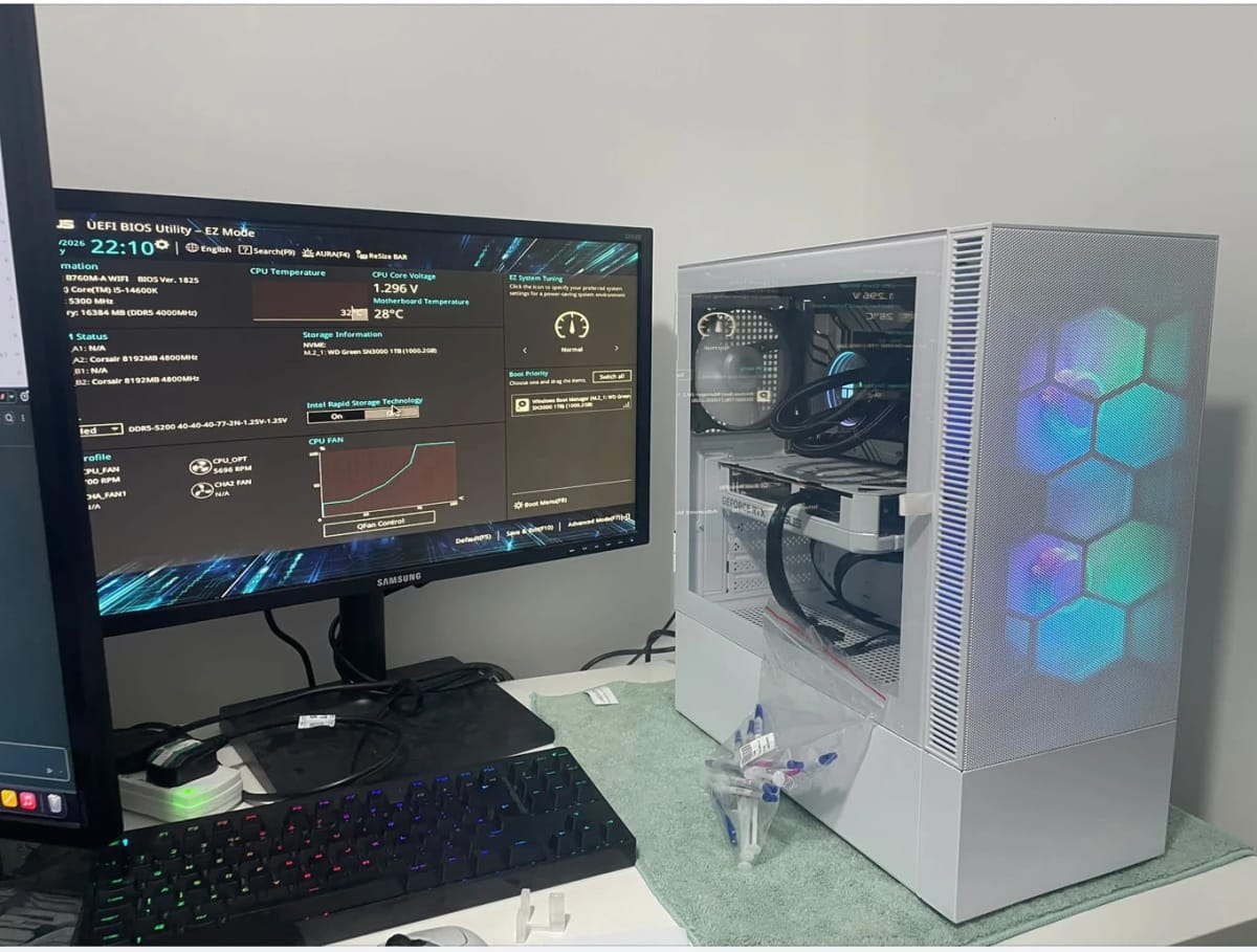 Customer PC with a new CPU and CPU cooler fitted, white case with a hexagon RGB front panel, running the BIOS on a monitor beside it